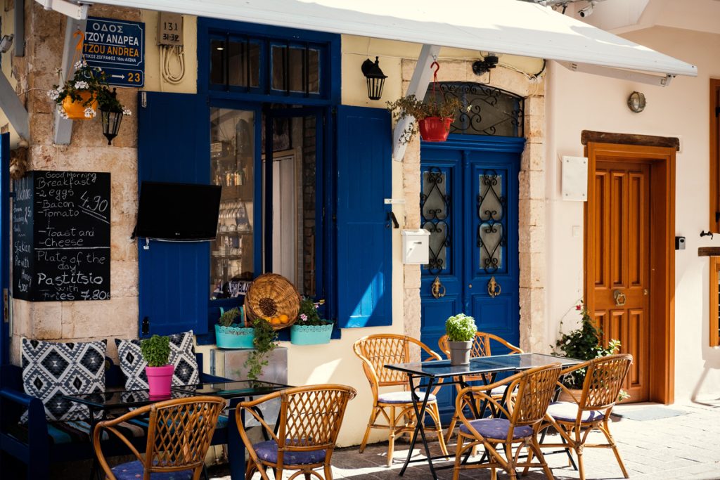 Typical Cypriot cafe with bright colours, blue painted wooden doors and rattan furniture